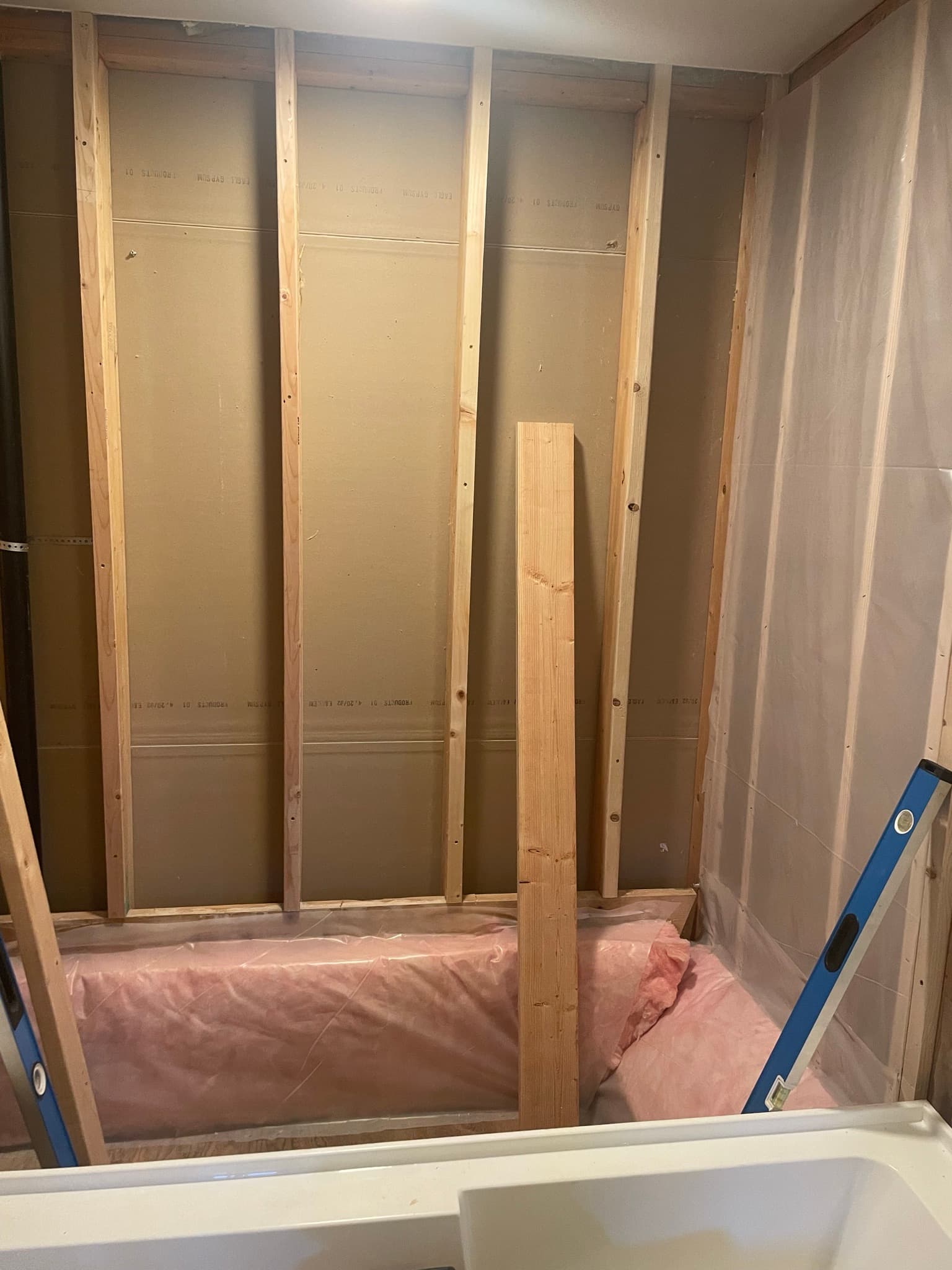 Tub area framed to studs with pink fiberglass insulation in the cavities, an additional 2x stud added for blocking.