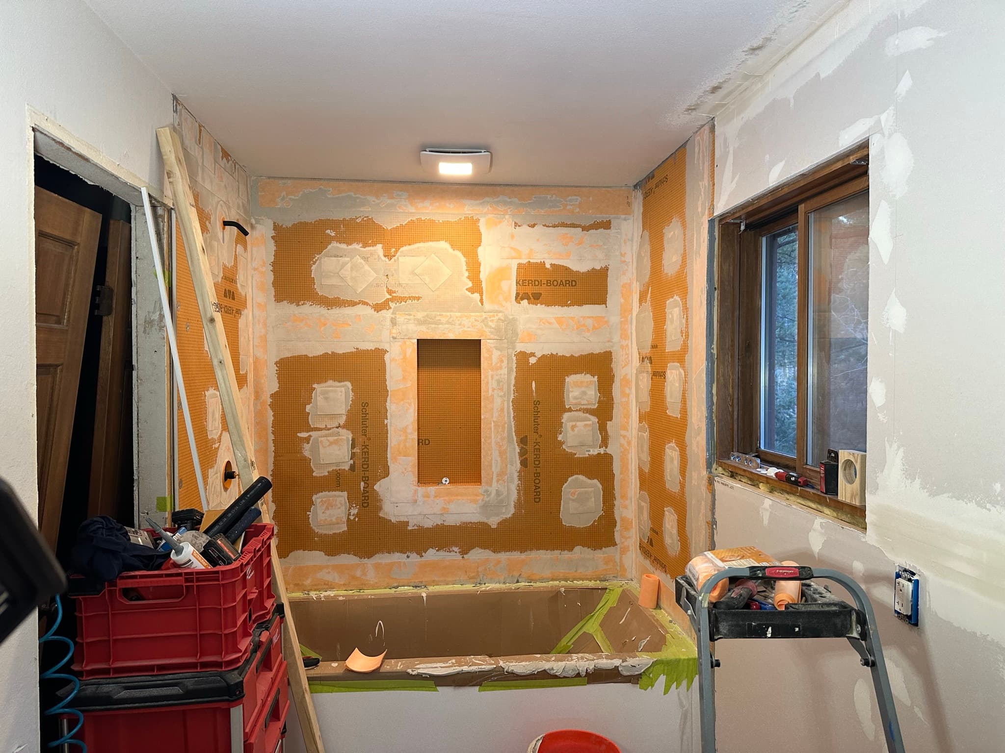 Kerdi-Board wall with white Kerdi-Fix waterproofing patches applied around every screw and at every penetration including the niche opening.
